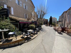 A street with outdoor seating at a restaurant, buildings on either side, and a clear sky. - Mougins Collection - Authentic House - Old Village of Mougins (Mougins)
