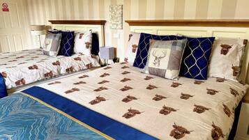 Une chambre d’hôtel avec deux lits, un papier peint à rayures, un panneau accroché au mur et un couvre-lit bleu à motifs.