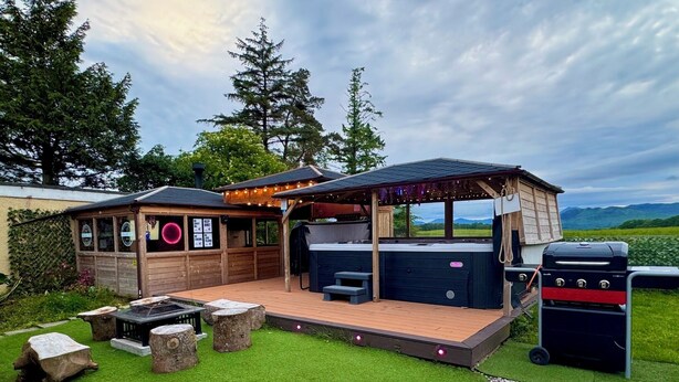 A hot tub area with a wooden deck, seating, and a grill. - FINN VILLAGE Mountain View Cottage Garden & XXL HOT TUB (Glasgow)