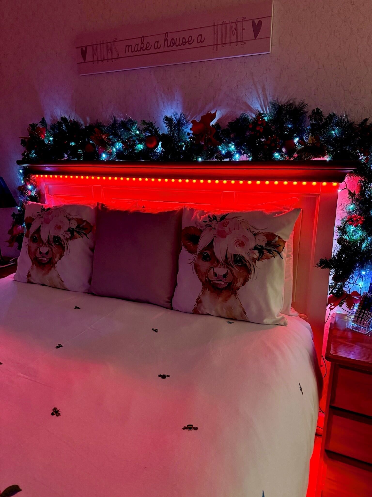 Ein Schlafzimmer mit Bett, Kissen, einem Wandschild und einem Weihnachtsbaum.