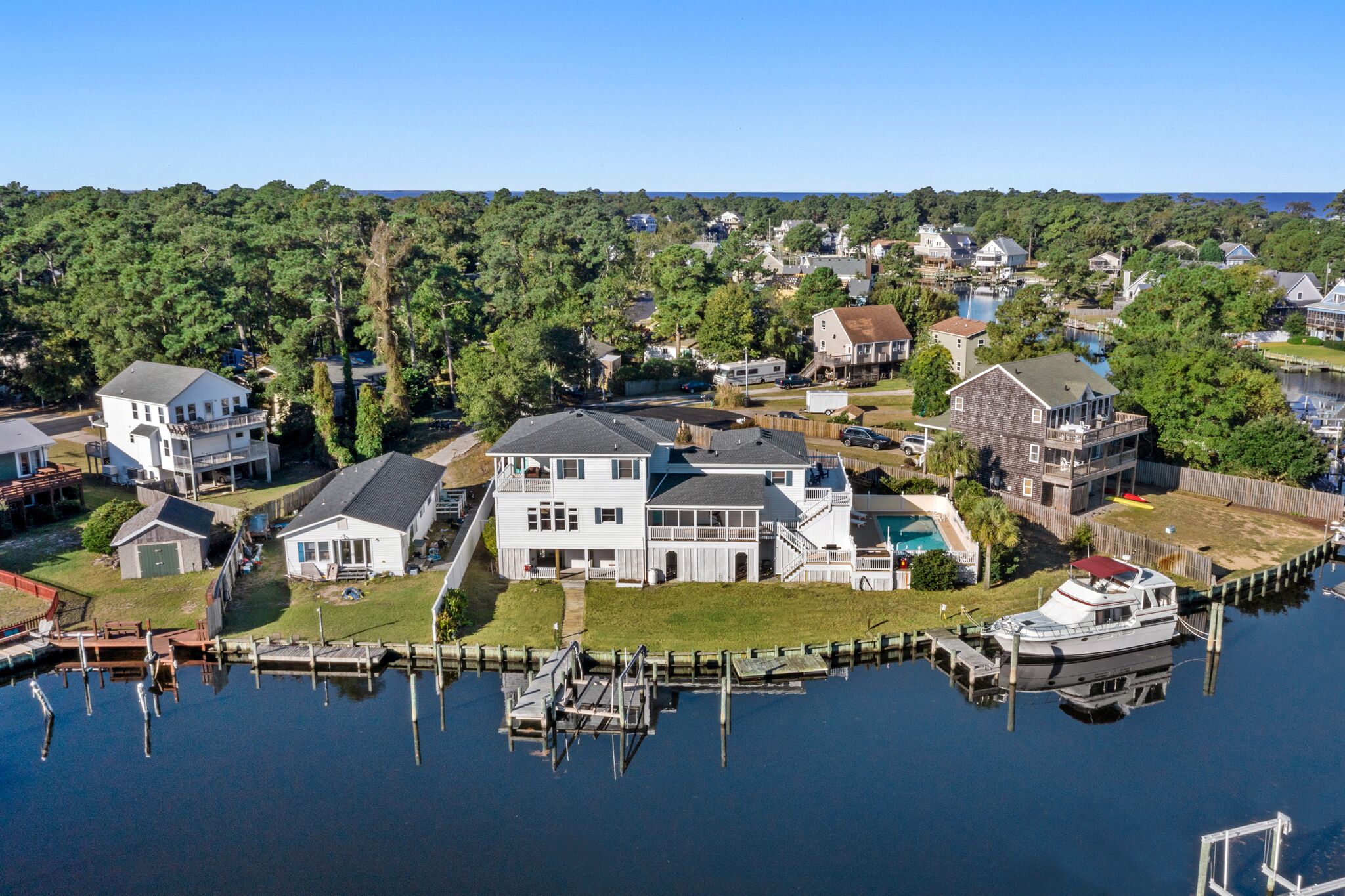 A waterfront property with a dock, a large house with a balcony, and a boat.