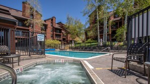 A hot tub area with a warning sign, a pool, and outdoor seating. - Location, Amenities and Value!  Near Ski Area Split Level Condo, Access to Pool, (Steamboat Springs)