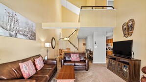 A spacious living room with a brown leather sofa, a wooden coffee table, and a television on a wooden cabinet. - Location, Amenities and Value!  Near Ski Area Split Level Condo, Access to Pool, (Steamboat Springs)