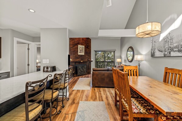 A modern kitchen with a dining area, wooden flooring, and a large window. - Cozy Ski Retreat | Ski Shuttle & Hot Tubs (Steamboat Springs)
