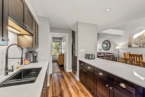 A modern kitchen with dark wood cabinets, a built-in oven, and a coffee maker. - Cozy Ski Retreat | Ski Shuttle & Hot Tubs (Steamboat Springs)
