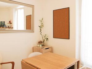 A room with a wooden desk, a mirror, a corkboard, and a small plant on a wooden cabinet.