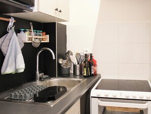 A kitchen with a sink, stove, and various utensils.