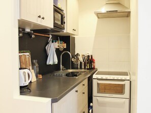 Een keuken met een magnetron, oven, spoelbak en diverse keukengerei.