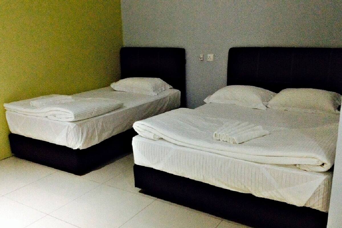 Two single beds with white linens, black headboards, and a tiled floor.