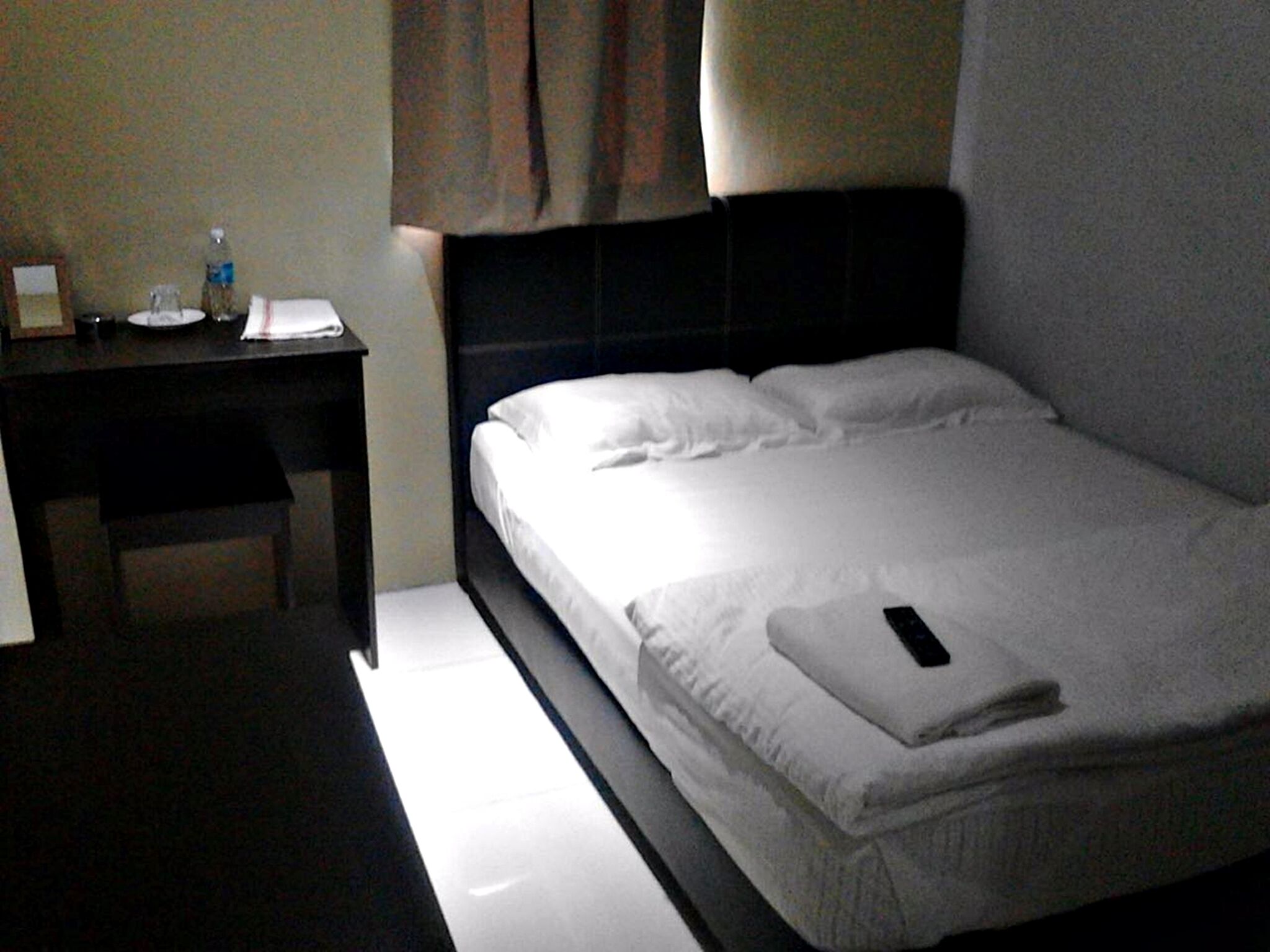 A hotel room with a bed, a bedside table, and a nightstand.