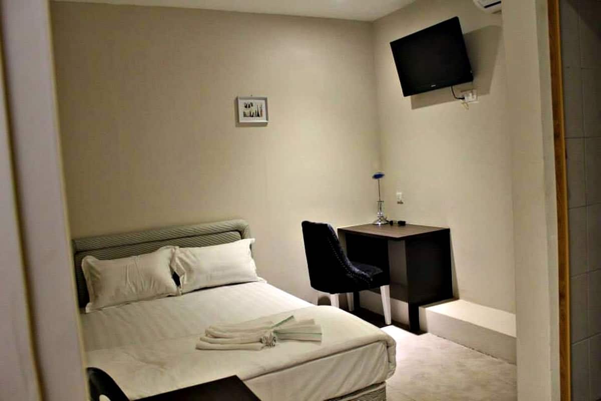 A hotel room with a bed, a desk, a chair, a television, and a picture on the wall.