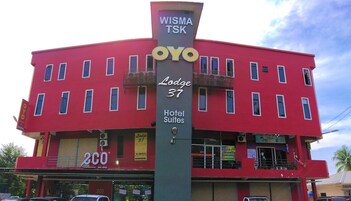 A red building with a sign for 'Lodge 37 Hotel Suites' and a '2CO eco-shop' at the ground level.