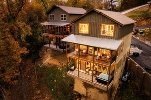 A two-story log cabin with a balcony and a deck, surrounded by trees.