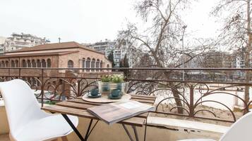 Un balcón con una mesa, sillas y vista a un edificio con arcos.