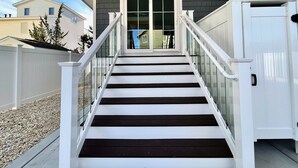 A staircase with white railings and dark steps leading to a glass door. - Stunning  Townhome, Private Elevator, Expansive Bay Views! (Sea Isle City)
