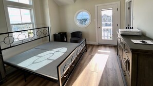 A bedroom with a bed, a window, a door, and a view of buildings outside. - Stunning  Townhome, Private Elevator, Expansive Bay Views! (Sea Isle City)