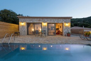 Un bâtiment en pierre doté d’une piscine, d’une terrasse en bois et d’un espace salon extérieur.