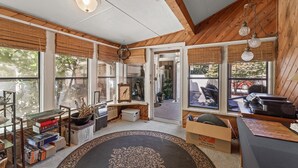 A room with a wooden ceiling, large windows, a black rug, and various items including a keyboard and books. - Beautiful 5bd Home with Pool Near LakePoint Sports (Cartersville)