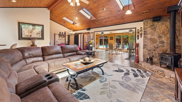A spacious living room with a large sectional sofa, a wooden coffee table, and a stone fireplace. - Beautiful 5bd Home with Pool Near LakePoint Sports (Cartersville)
