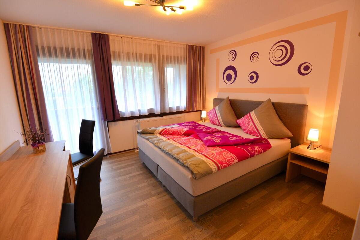A bedroom with a bed, a desk, and a chair.