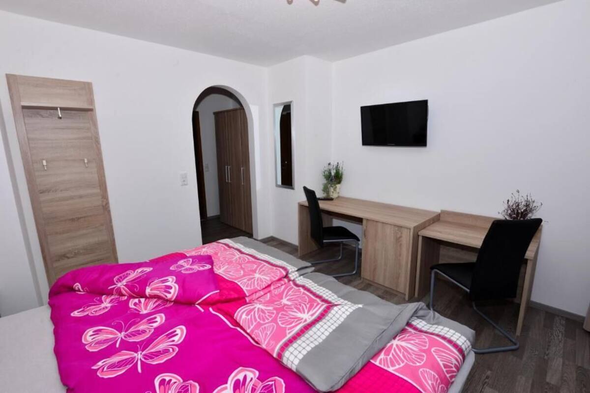 A bedroom with a bed, a desk, and a TV.