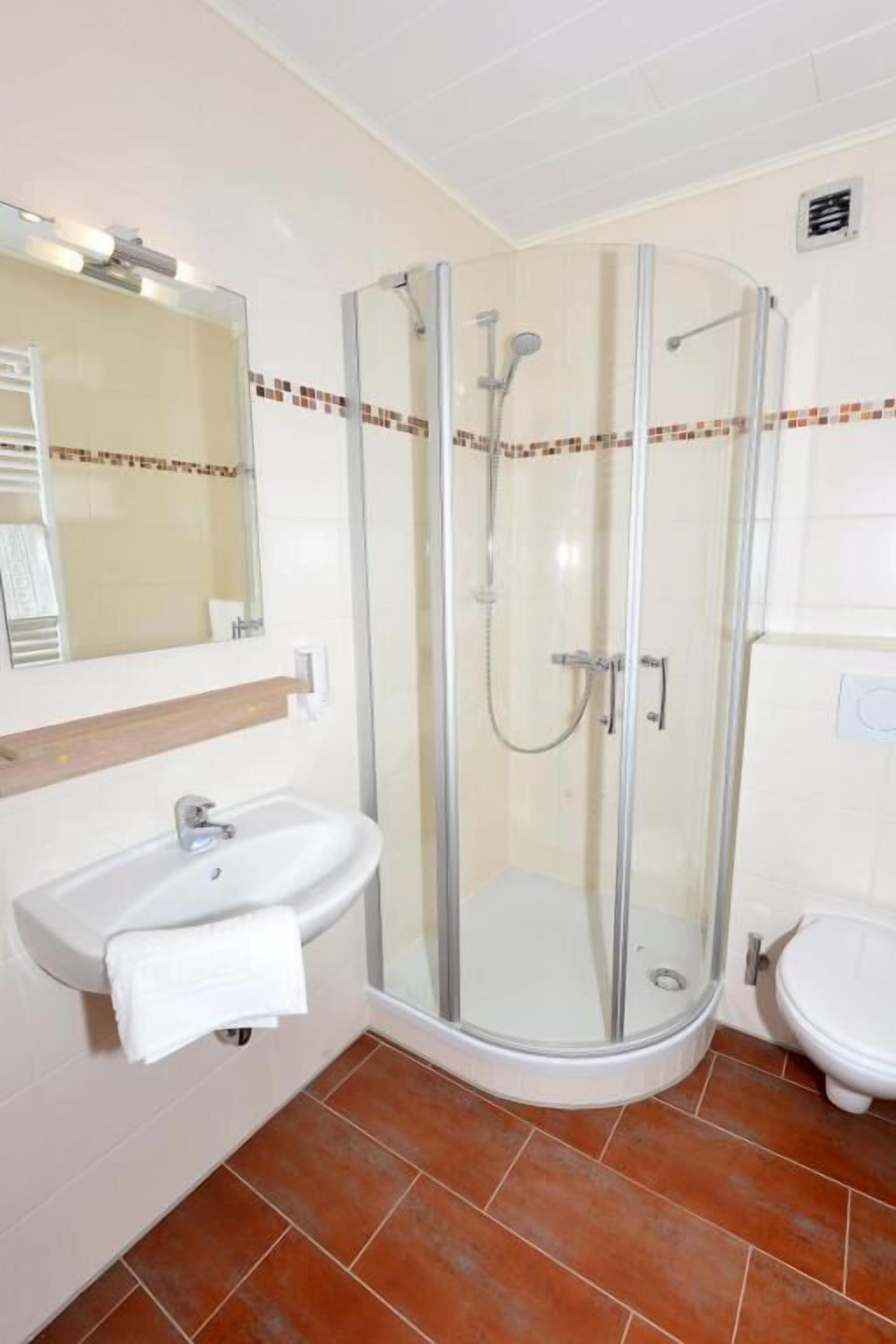A bathroom with a glass-enclosed shower, a sink, and a toilet.