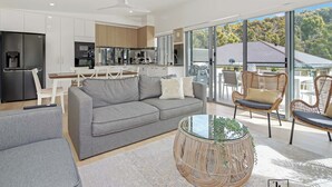 En moderne stue med en grå sofa, et rundt fletningsbord og fletstole.