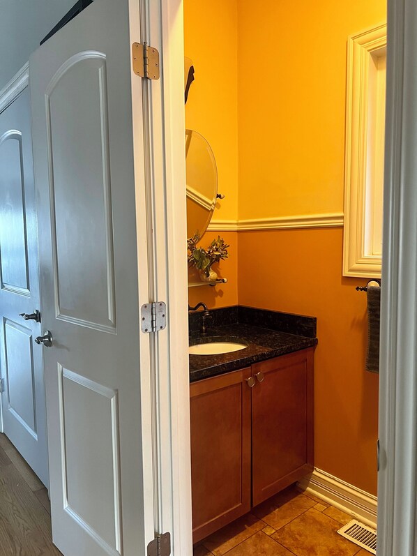 Un baño con una puerta blanca, un lavabo con espejo y una toalla colgada en la pared.