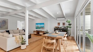 A spacious living area with a wooden dining table, a sofa, and a large window.