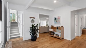 A spacious living area with a staircase, a sofa, a wooden cabinet, and a potted plant.