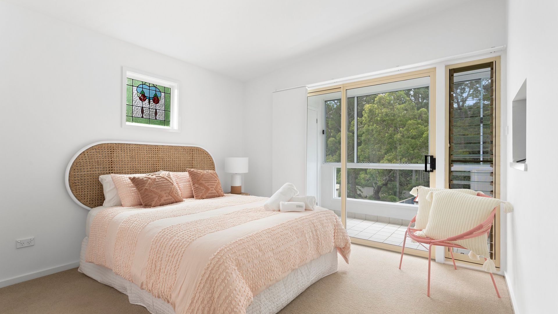 A bedroom with a bed, a bedside table, a chair, and a window.