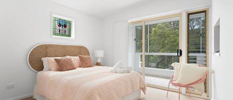 A bedroom with a bed, a bedside table, a chair, and a window.