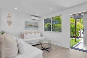 A modern living room with a white sofa, a small round table, and a painting on the wall.