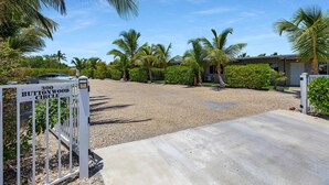 A gated driveway leading to a residential property with a gravel driveway, palm trees, and a sign indicating '300 Buttonwood Circle'. - 5. Key Largo Waterfront Studio / Kayak & Reef (Key Largo)