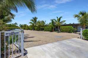 A gated driveway leading to a residential property with a gravel driveway, palm trees, and a sign indicating '300 Buttonwood Circle'. - 5. Key Largo Waterfront Studio / Kayak & Reef (Key Largo)