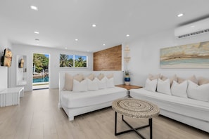 A modern living room with a white sofa, a coffee table, and a view of a pool. - 5. Key Largo Waterfront Apartment | Reef & Relax (Key Largo)
