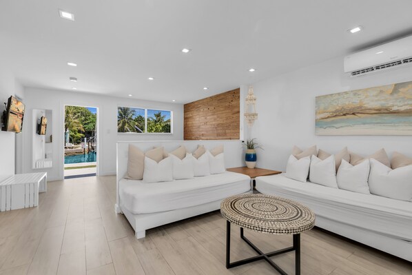 A modern living room with a white sofa, a coffee table, and a view of a pool. - 5. Key Largo Waterfront Apartment | Reef & Relax (Key Largo)