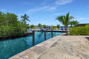 A waterfront property with a dock, clear blue water, and lush greenery.