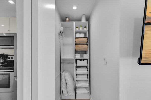 A walk-in closet with shelves for folded towels, a hanging rack for robes, and a small shelf with potted plants. - 5. Key Largo Waterfront Apartment | Reef & Relax (Key Largo)