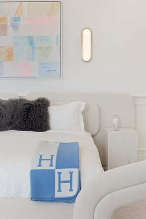 A neatly made bed with a blue blanket, a fluffy pillow, and a bedside table with a bottle. - Chateau Beverly Hills by Stay Awhile Villas (Beverly Hills)