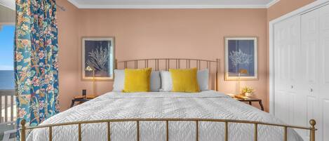 A bedroom with a bed, a ceiling fan, and two framed pictures on the wall.