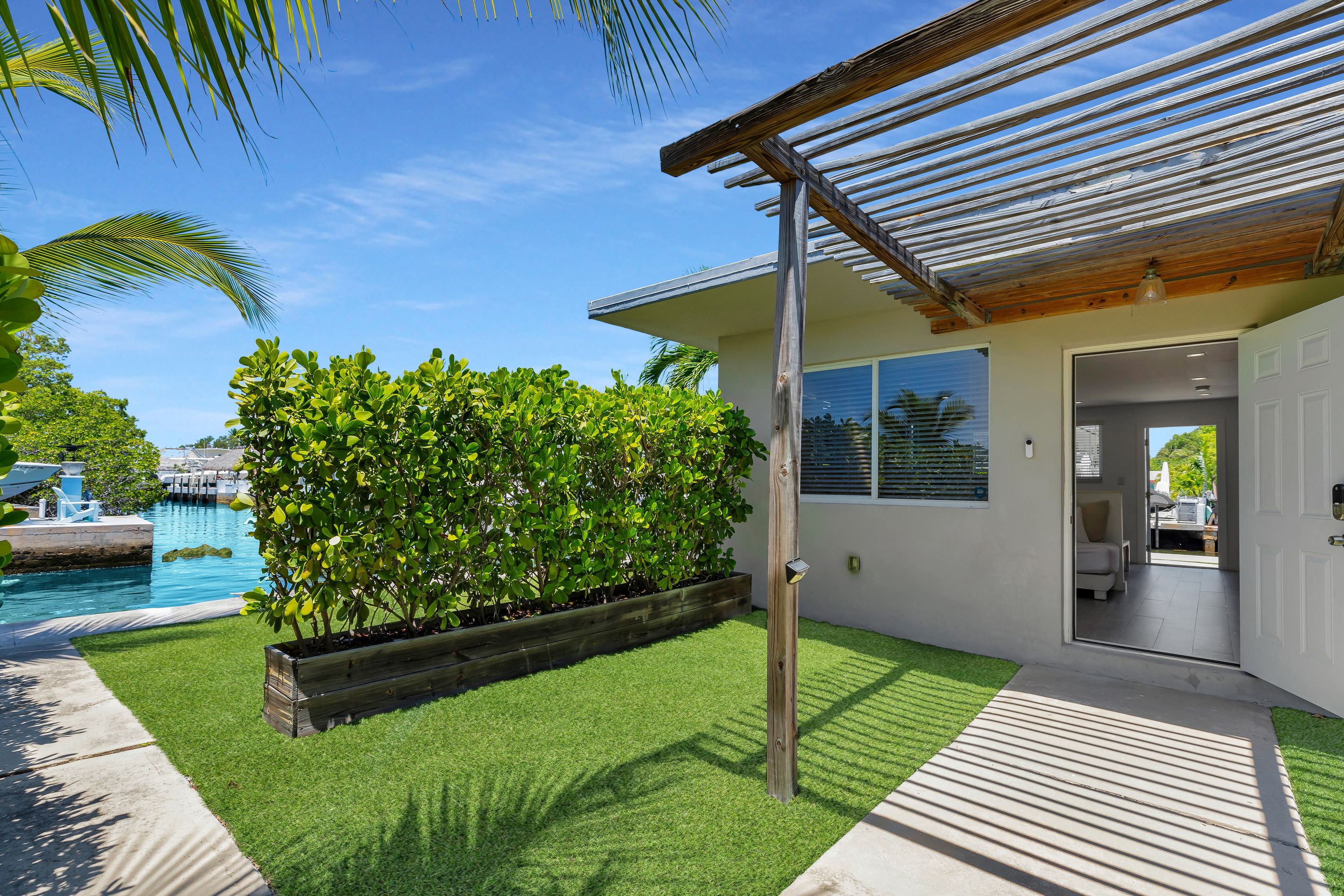 A modern house with a pool, a wooden pergola, and a well-maintained lawn.