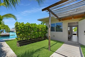 Una casa moderna con piscina, una pérgola de madera y un césped bien cuidado.