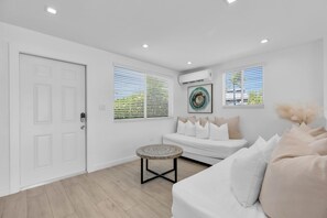 A modern living room with a white sofa, a round coffee table, and a door with a keypad lock. - 6. Key Largo Waterfront Studio | Dock, Snorkel (Key Largo)