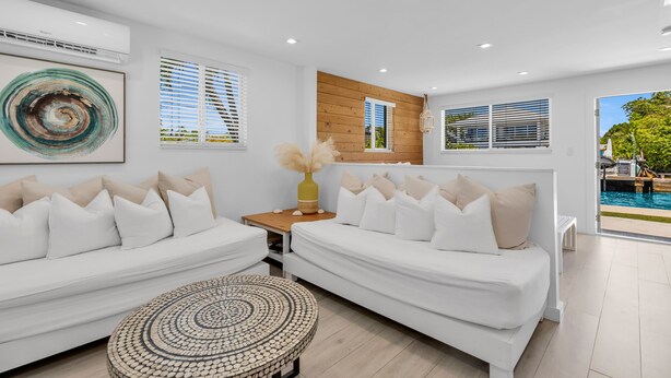 A modern living room with two white sofas, a round coffee table, and a wooden accent wall. - 6. Key Largo Waterfront Studio | Dock, Snorkel (Key Largo)