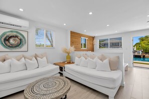 A modern living room with two white sofas, a round coffee table, and a wooden accent wall. - 6. Key Largo Waterfront Studio | Dock, Snorkel (Key Largo)