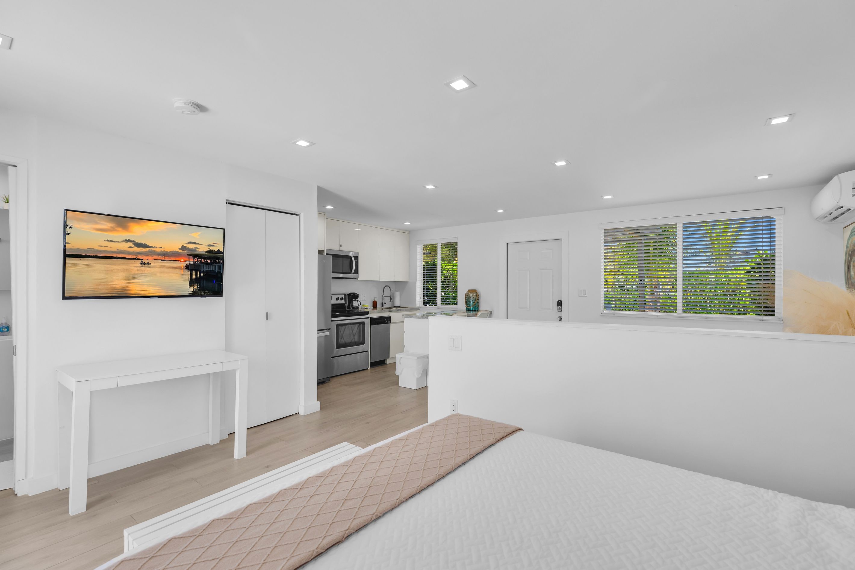 A modern kitchen with white cabinets, a microwave, and a sink.