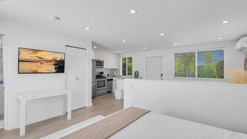 A modern kitchen with white cabinets, a microwave, and a sink.