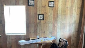 A room with wooden walls, a window, a desk with a chair, and a framed certificate on the wall. - Delightful kitchenette style tiny home with loft. (Overton)