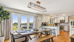 A modern kitchen with wooden flooring, a dining area with a bench, and a view of the outdoors.